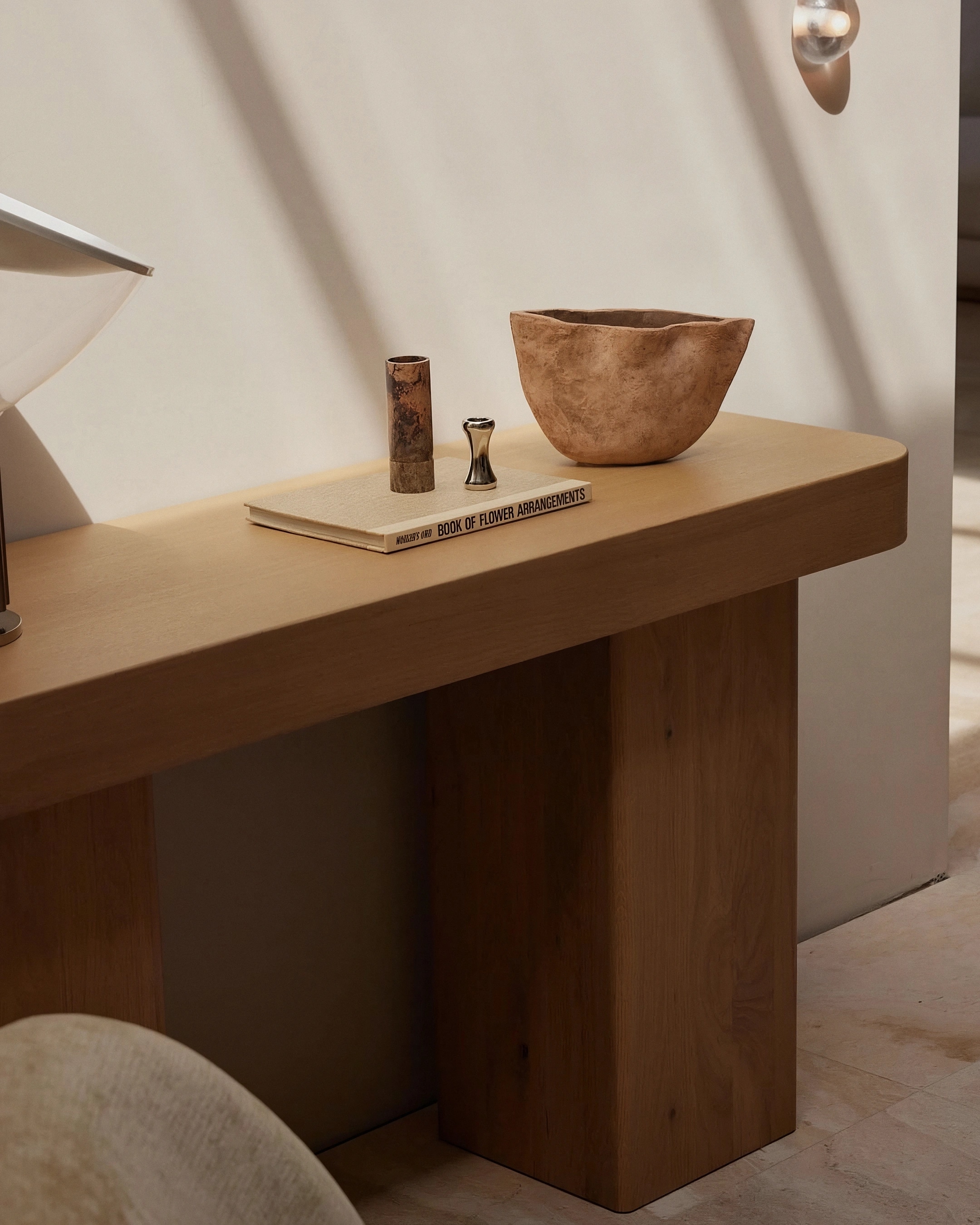 Oak console at Elena House, with a book, ceramic vessels and a sculptural lamp