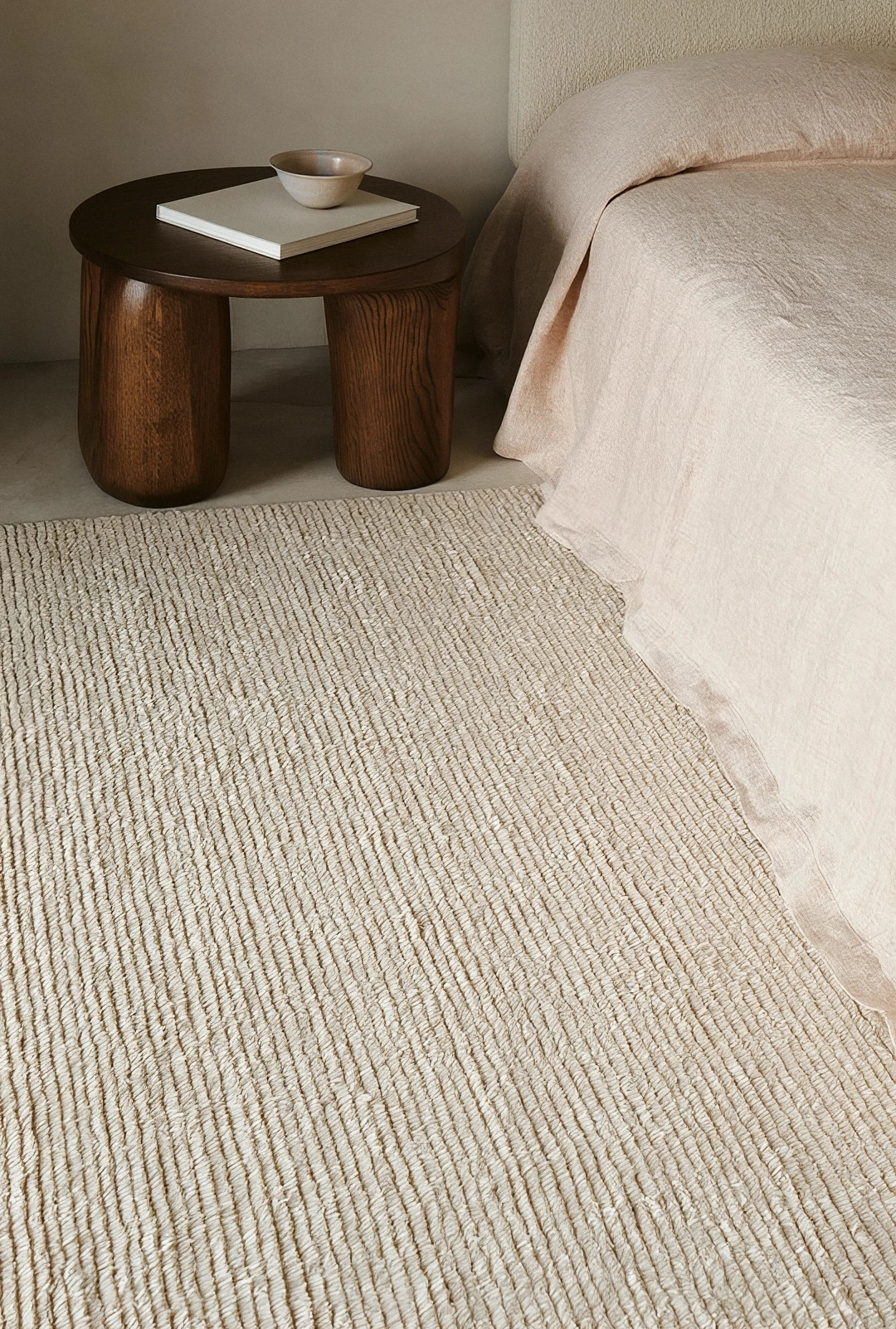 Wooden stool beside a bed on a ribbed rug at Bossa Nova Vineyard